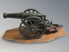 A die cast metal scale model of a cannon on wooden plinth, length 44 cm.