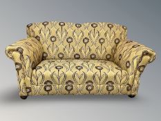 A two seater Edwardian settee upholstered in Arts and Crafts style floral upholstery,