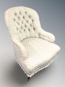 An Edwardian lady's armchair in buttoned upholstery, width 67 cm.