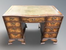 A walnut serpentine-front nine drawer twin-pedestal writing desk with leather inset top,