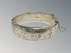 An engraved silver bangle with safety chain, diameter 60 mm x 56 mm, Birmingham 1961.