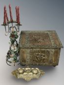 A decorated embossed metal coal receiver, a cast brass desk stand and a candelabrum.
