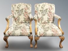 A pair of reproduction open armchairs on carved claw and ball feet, with floral upholstery,