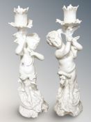 A pair of continental pottery candlesticks in the form of cherubs, height 29 cm.