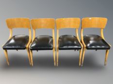 A set of sixteen curved and laminated wood dining chairs with black vinyl seats.