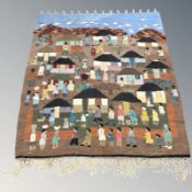 A hand woven pictorial wall hanging depicting a village scene, 170 cm x 140 cm.