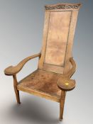 An Arts & Crafts carved oak and studded leather armchair,