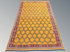 A vintage woolen rug with repeat lattice design on orange ground, 254 cm x 150 cm.