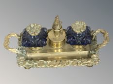 A brass desk stand with pair of blue glass ink wells, width 24 cm.