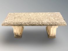A weather concrete rectangular garden bench on pedestal supports,