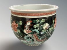 A Chinese porcelain planter depicting a peacock amongst foliage on black ground, height 18.5 cm.