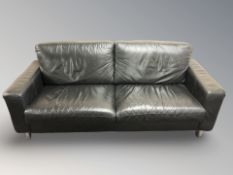 A modern black leather three seater settee on chrome cylindrical feet, 201 cm x 89 cm x 85 cm.
