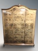 A figured walnut triple door wardrobe on pad feet, with keys,