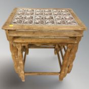 A nest of three Danish oak tables with tiled tops, width 54 cm.
