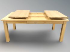 A modern solid oak extending dining table fitted a drawer,