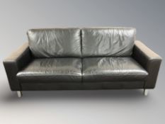 A modern black leather three seater settee on chrome cylindrical feet, 201 cm x 89 cm x 85 cm.