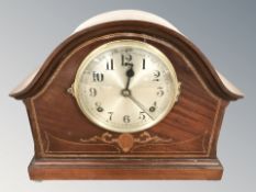 An inlaid mahogany mantel clock with silvered dial, striking on a gong, with pendulum, height 28 cm.
