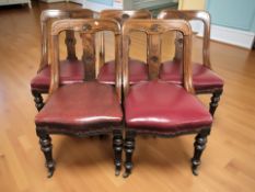 A set of five carved mahogany dining chairs with burgundy leather seats.