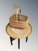 An eastern brass topped bobbin table, diameter 57 cm, a wicker basket and a brass easel stand.