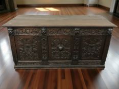 An 18th century panelled and heavily carved oak blanket chest, 155 cm x 65 cm x 75 cm.