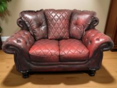 A Chesterfield style oxblood buttoned leather two seater settee, 170 cm W x 105 cm D x 102 cm H.