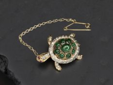 An 18ct gold turtle brooch, set with a shell of cabochon emeralds within a diamond set border,