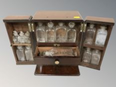A 19th century mahogany double door chemist's bottle chest containing glass bottles, height 26 cm.