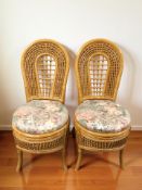 A pair of wicker chairs with floral seat pads.