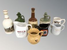 A group of ceramic jugs with whisky advertising and four empty decanters.