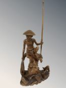 An eastern carved hardwood figure of a fisherman, height 95 cm.