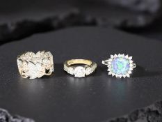 Three decorative silver dress rings, including a simulated opal example,