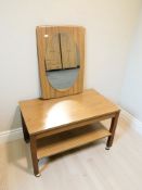 A teak effect low table on castors, width 70 cm, and a teak backed mirror.