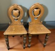 A pair of Victorian oak hall chairs.