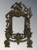 A patinated metal easel picture frame decorated with cherubs, height 35 cm.