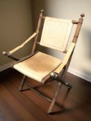 A folding bamboo effect armchair with faded tan leather sling seat and armrests, width 60 cm.