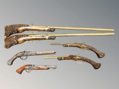 A group of decorative flintlock pistols, two similar muskets.