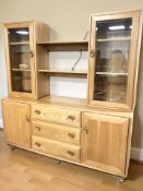 An Ercol light elm sideboard, with bookshelf and glazed cabinets above,