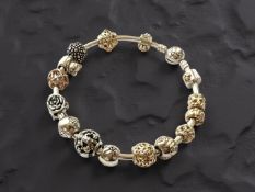 Pandora : A silver and 14ct gold charm bracelet/bangle, inner diameter 67mm in approximately,