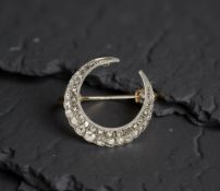 An early 20th century graduated old cut diamond crescent brooch, approximately 1.5ct, width 31.