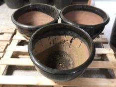 A set of three of black glazed earthen ware circular garden planters,