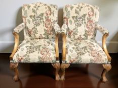 A pair of reproduction carved armchairs on claw and ball feet.