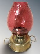 A late Victorian brass and cranberry glass oil lamp, height 41 cm.