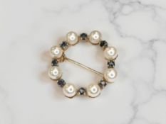 A cultured pearl and sapphire wreath brooch, set in 9ct gold, diameter 23mm.