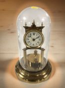 A brass timepiece under glass dome, height 30 cm.