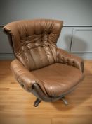 A Scandinavian brown buttoned leather swivel lounge armchair.