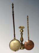 Two bed warming pans and a large brass candlestick, height 60 cm.