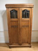 An early 20th century carved and glazed oak double door cabinet with shelved interior,