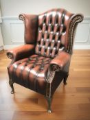 An oxblood button leather wing back armchair,