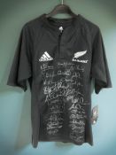 An Adidas New Zealand All Blacks rugby shirt, with various signatures, size M.
