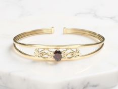 A 9ct yellow gold torsion bangle set with a garnet CONDITION REPORT: 3.4g gross.